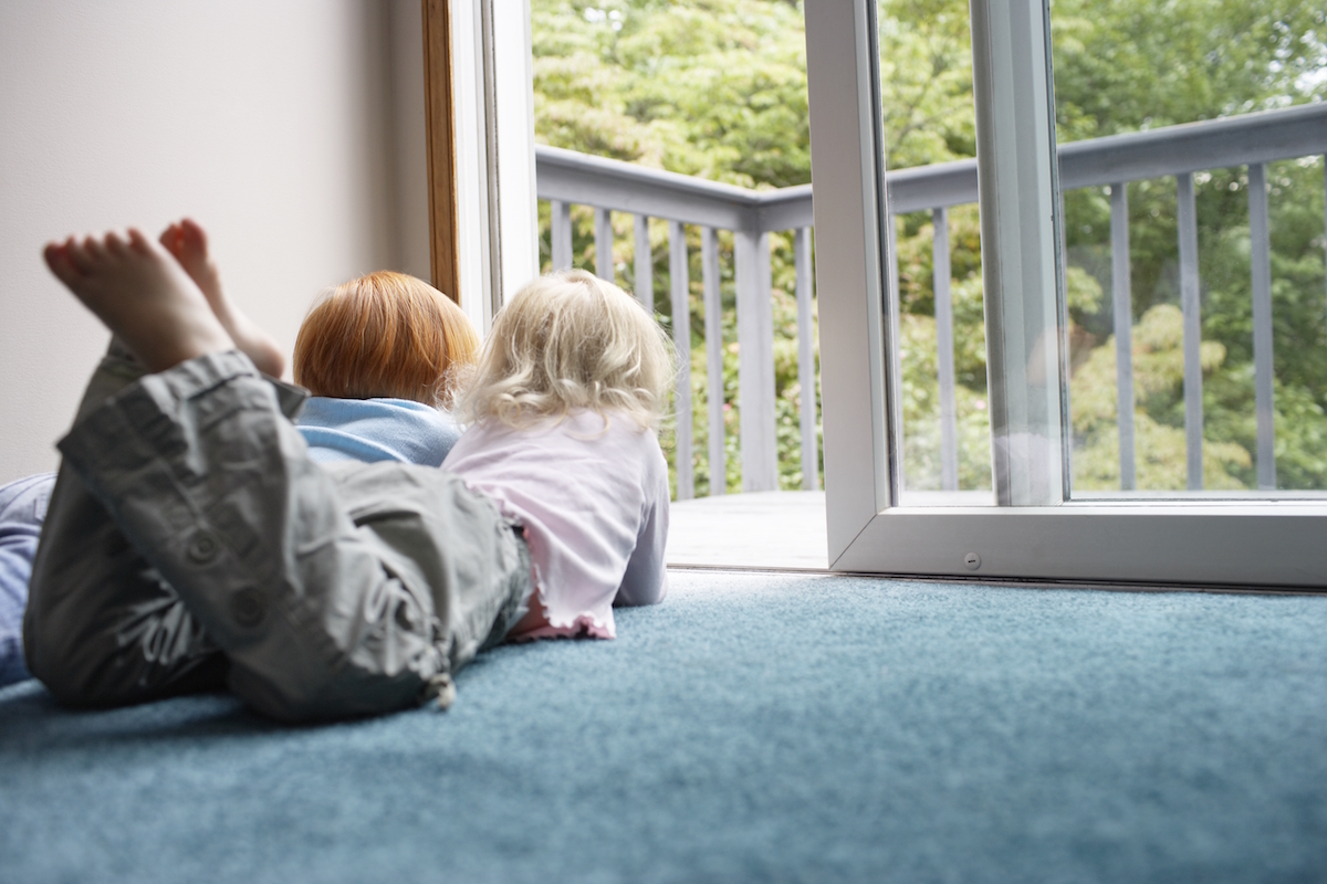 dobre okna PCV profil Synego EUROPLAST Lubin dzieci leża na dywanie i patrzą przez okno